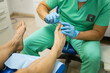 An unrecognizable podiatrist cuts the toenails during the pedicure procedure. Professional pedicure in the beauty salon. The beautician cuts the skin with his nails and performs professional pedicure.