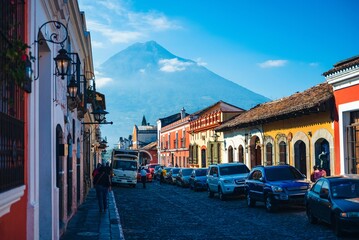 Canvas Print - Cobblestone street in an old town, with colorful buildings on the background of a mountain