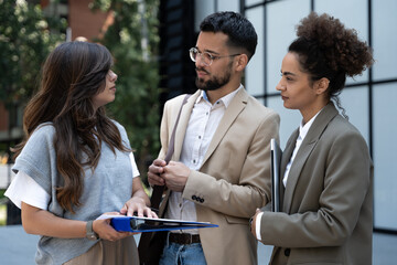 Wall Mural - Group of coworkers walking outside in front of office buildings discuss about business plan. Businesspeople marketing sale experts talking ideas and marketing tactics