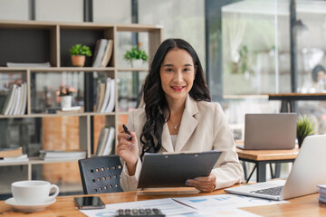 Wall Mural - Cheerful business lady working on laptop in office, Asian happy beautiful businesswoman work in workplace. Attractive female employee office worker smile