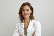 Portrait Of A Smiling Female Doctor Standing With Arms Crossed Over White Background