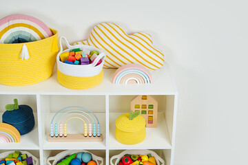 Wall Mural - White shelving with rainbow wooden toys and colorful storage baskets. Interior design. Organizing and storage ideas in nursery.