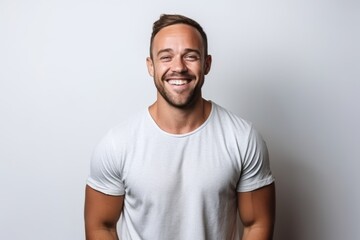 Wall Mural - Portrait of handsome young man laughing and looking at camera while standing against white background