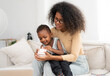 © Nassorn - Multiethnic woman sits in living room have fun relaxing at home with her little son. Cheerful biracial child happy smile bonding with his curly hair mother. Enjoyment and love in childhood lifestyle