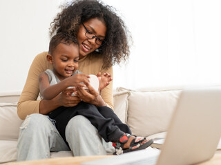 multiethnic woman sits in living room have fun relaxing at home with her little son. cheerful biraci