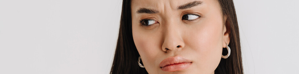 Asian puzzled woman wearing t-shirt frowning and looking aside