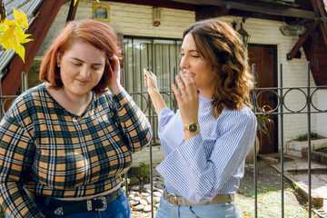 two latin women enjoying talking and smiling at each other outside at noon, in Buenos Aires.