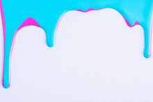 Pink And Blue Mixed Drops Of Paint Flow Down On White Canvas. Abstract Art. Colorful Paint Dripping On The White Wall
