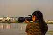 A female photographer taking photo of water birds at a lake near Kolkata.