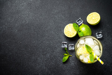 Mojito with rum, lime, mint and ice on black background. Tradition Summer drink. Flat lay with copy space.