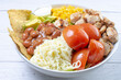 Bowl salad with pieces of roasted pork, grated cheese, beans, corn, tomato, nachos, lettuce, with house mayonnaise