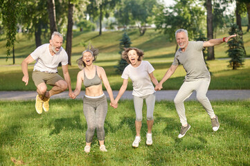 Group of healthy runners team jumping in the air at city park during morning training.