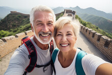 A Happy Elderly Tourist Couple Take A Selfie In China With The Great Wall In The Background. Travel Retirement Concept. AI Generated.
