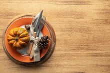A Plate With Cutlery Is Decorated For Thanksgiving With Pumpkins And Autumn Products On A Wooden Table, Top View