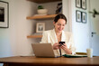 © sepy - Attractive young woman using mobile phone and laptop and working at home