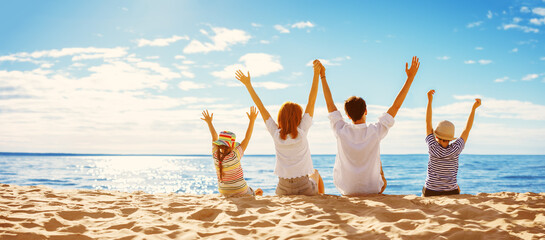 Parents with their child sitting in the sand on the seashore in sunny day.