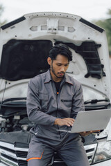 car service, repair, maintenance concept - Asian auto mechanic man or Smith writing to the clipboard at workshop warehouse, technician doing the checklist for repair machine a car in the garage,banner