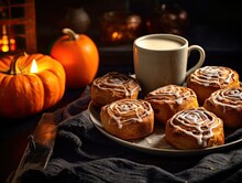 Freshly Baked Halloween Cinnamon Rolls With Spider Web Ornament With Cup Of Coffee And Orange Halloween Pumpkins In The Background. Generative AI