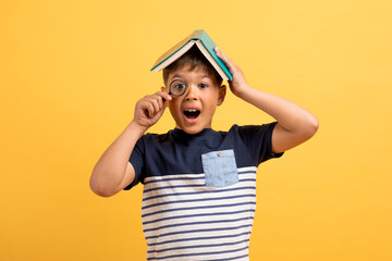 Poster - Excited kid cute boy with book on head holding magnifier