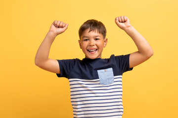 Wall Mural - Emotional happy boy raising hands up, clenching fists