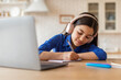 © Prostock-studio - Schooler girl doing homework at laptop taking notes at home