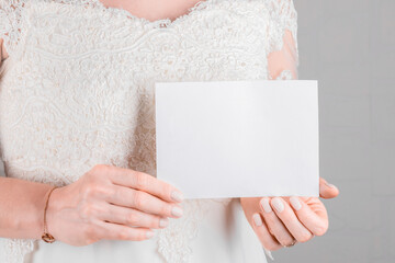 Wall Mural - Bride holding wedding stagionery invitation card mockup 7x5 on white wall background. Minimal stile blank mockup, thank you card, greeting card, wedding template