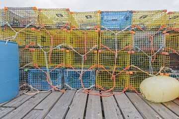 Lobster traps and bouy stacked on a pier.