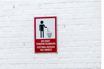 Poster - No garbage disposal sign. A banner prohibiting throwing garbage in nature in the area. The sign is on a white wall with the words in English and Polish meaning it is forbidden to throw garbage