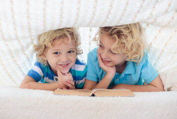 Wall Mural - Child reading book in bed. Kids read books.