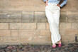 © Olha Ye - a successful young woman in white trousers and a blue shirt. the woman is leaning against the wall. A shortened shot of a woman's legs in classic trousers. copy space