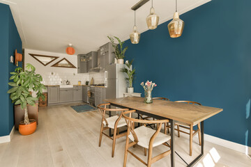a dining room with blue walls and white flooring the room is decorated with wooden furniture, pots and plants
