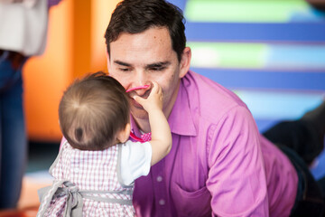 Wall Mural - Young father playing with his baby daughter. Early stimulation for toddlers concept.