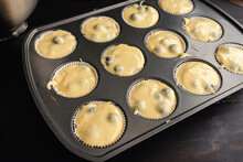 Muffin Tin Lined With Paper Wrappers And Filled With Blueberry Muffin Batter: Unbaked Blueberry Muffin Batter In A Muffin Pan With Kitchen Tools