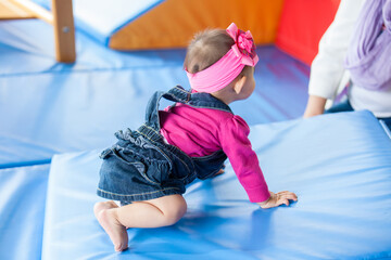 Wall Mural - Beautiful ten months baby girl crawling on a colorful background. Early stimulation for toddlers concept.