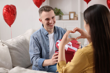 Wall Mural - Man opening gift box from his girlfriend indoors. Valentine's day celebration