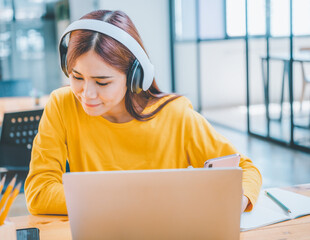 Wall Mural - young student wearing headphones studies online, distance learning, and keeps up to date on the global coronavirus pandemic.