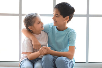 Poster - Little boy with his sister hugging near window