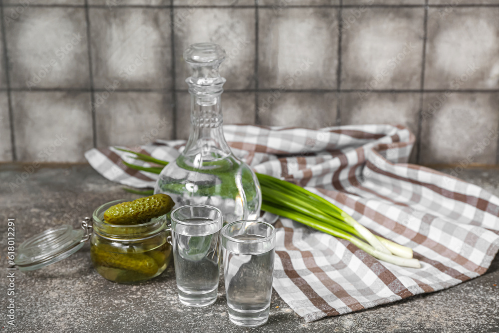 Shots and decanter of cold vodka with pickles on table