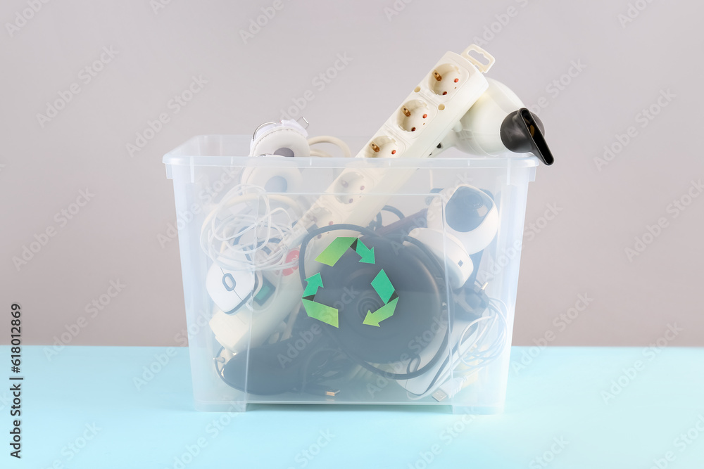 Recycle bin with different household appliances on color background