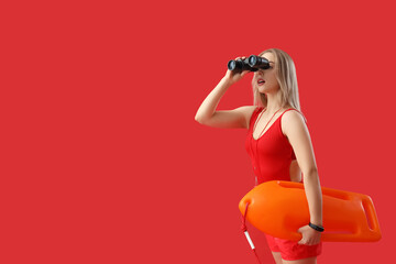 Wall Mural - Female lifeguard with binoculars and rescue buoy on red background