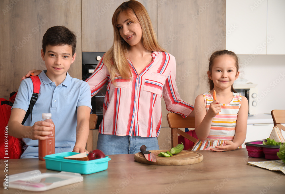 Mother preparing school lunch for her little children in kitchen