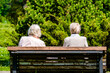 Two elderly women are sitting on a park bench