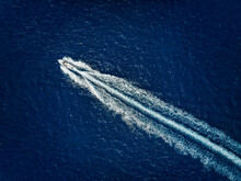 High Aerial View Of A Motor Speeboat Traveling Over Blue Ocean And Leaving A Trail Of Fom And Bubbles