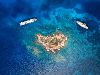 Wall Mural - a beautiful reef in the ocean surounded by turquoise sea and moored luxury yachts as seen at the coa