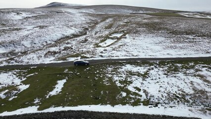 Canvas Print - Drone shot of a car stopped on a narrow road in snowy field