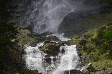 Poster - Majestic waterfall cascading down a sloping hillside, creating a picturesque and serene atmosphere