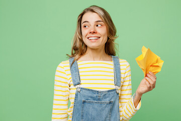 Wall Mural - Sick unhealthy ill allergic woman has red watery eyes runny stuffy sore nose suffer from allergy trigger symptoms hay fever hold paper napkin looking aside on area isolated on plain green background.