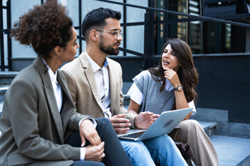 Business people outdoor meeting. Company staff businessmen and businesswomen in suits are sitting on the steps of the stairs. Working break. Teamwork and brainstorming. Successful managers and team