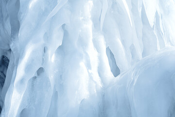 Blue ice and icicles on the rocks of Ogoy island, Baikal lake, Siberia, Russia. Abstract winter nature background with copy space.