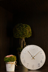 decorative flowers stand on a dark shelf next to a white clock, home decor